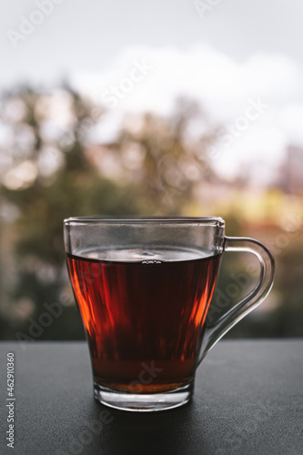A cup of hot tea standing by the window at sunset