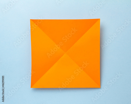 Step-by-step photo instruction on how to make a bookmark for a book in the form of an orange tiger from paper with your own hands. The symbol of the new year 2022. Step 1. Fold the sheet diagonally