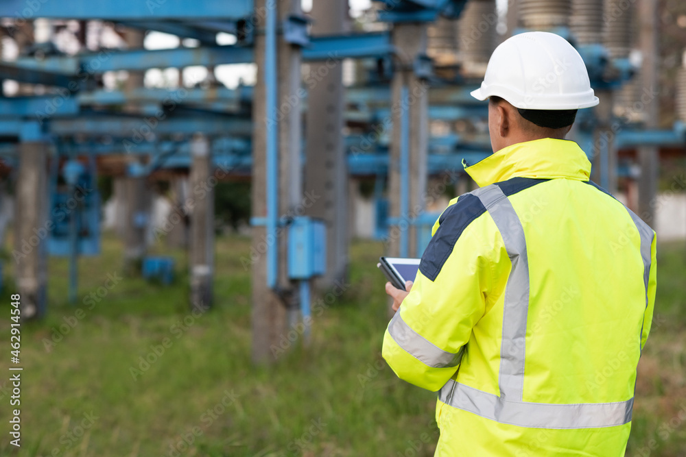Electrical worker engineer a working with digital tablet, power near tower with electricity. Energy business technology industry concept. Electrical engineer studying reading on tablet. Electrical worker engineer a working with digital tablet, power near tower with electricity. Energy business technology industry concept. Electrical engineer studying reading on tablet.