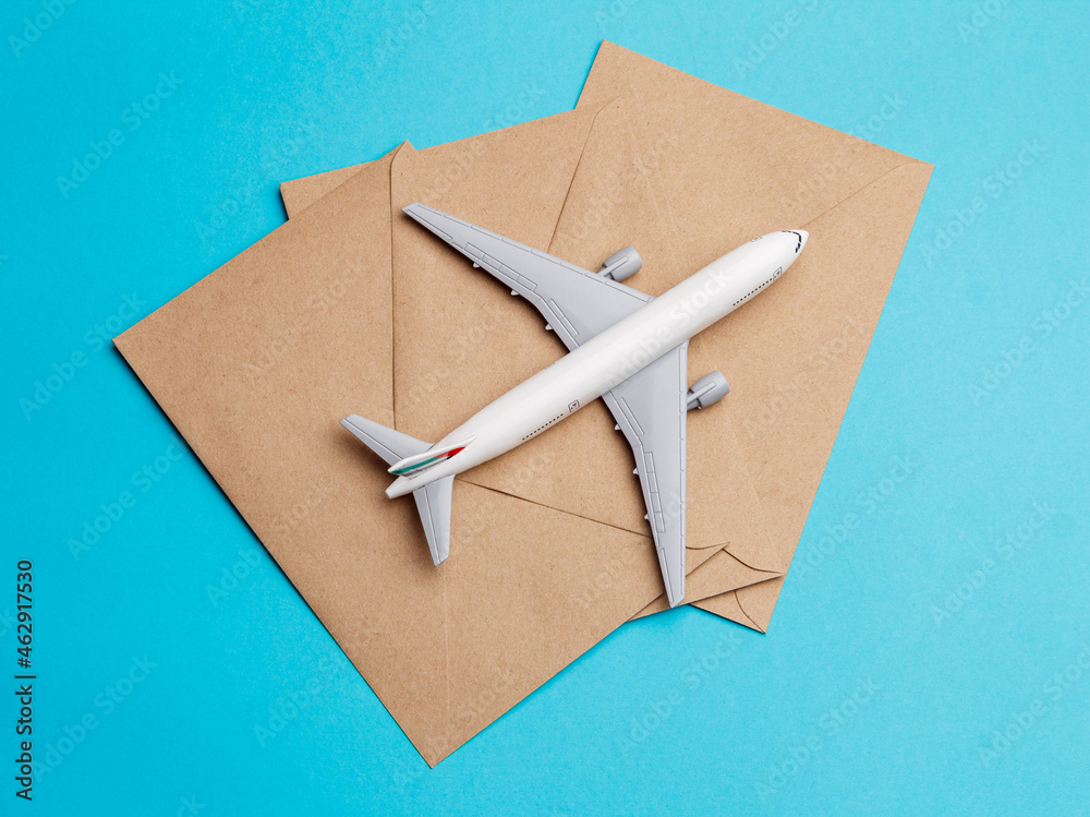 The concept of transporting mail and messages by plane. A white toy airplane is flying on a journey. Top view. Turquoise background. A place to copy. Free space The concept of transporting mail and messages by plane. A white toy airplane is flying on a journey. Top view. Turquoise background. A place to copy. Free space