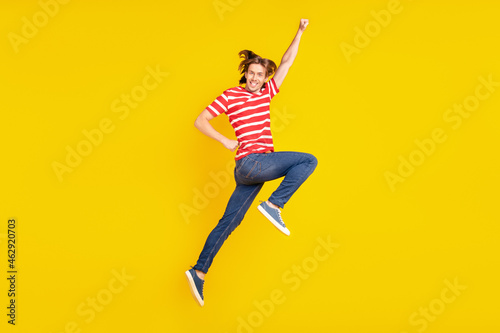 Photo of sweet charming young guy dressed red t-shirt jumping high smiling isolated yellow color background