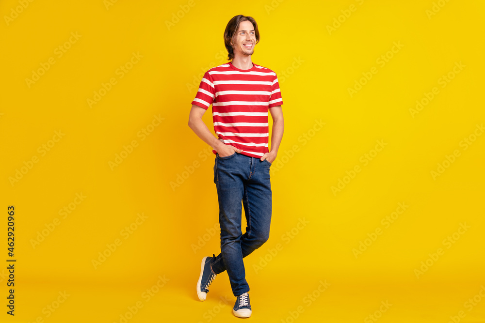 Photo of charming pretty young guy dressed red t-shirt walking arm pockets looking empty space smiling isolated yellow color background Photo of charming pretty young guy dressed red t-shirt walking arm pockets looking empty space smiling isolated yellow color background