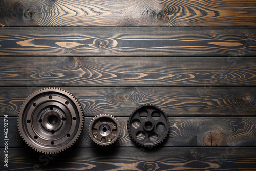 Gear wheels on the brown wooden flat lay workbench background with copy space.