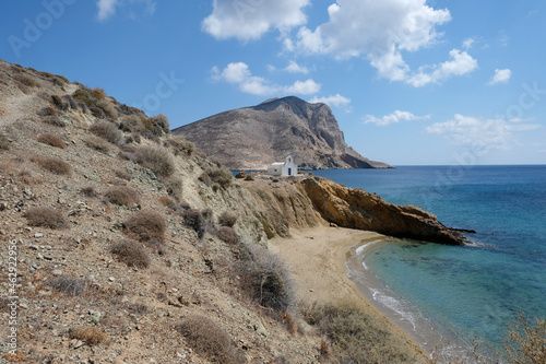 Anafi island - sandy beach and the small church of Agioi Anargyroi, on the back Kalamos Rock monolith. Cyclades islands, Greece
