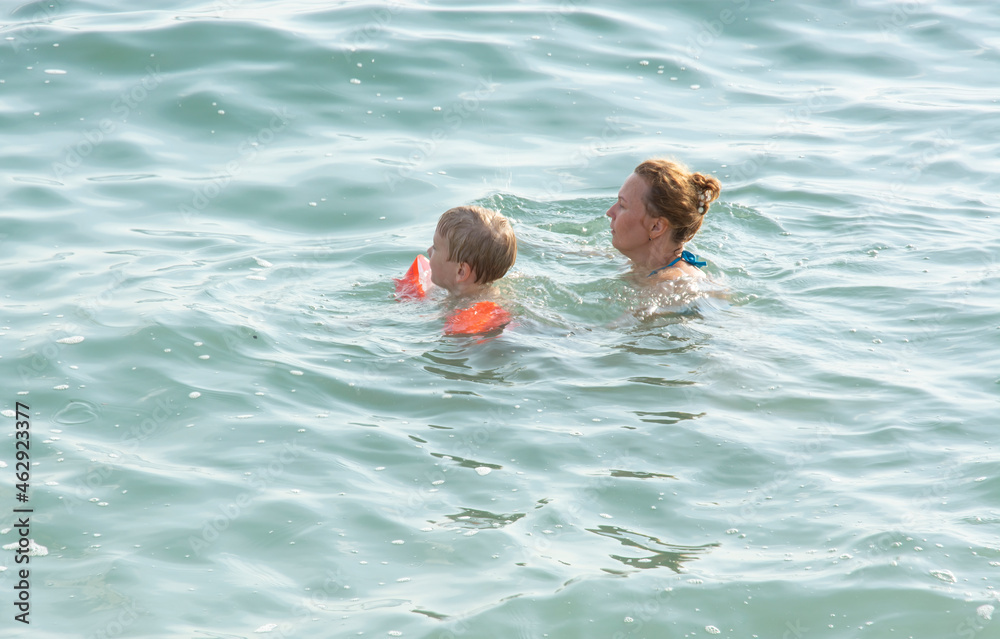 mom teaches the boy to swim in the sea. sea holidays and travel.