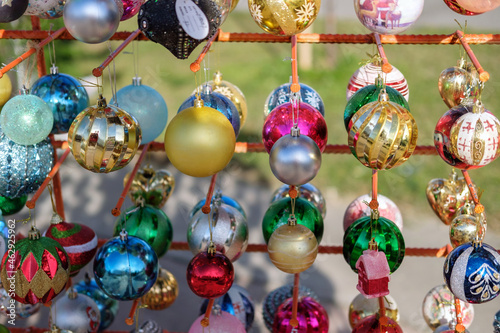 Various colorful Christmas balls on the stand on a blurred background