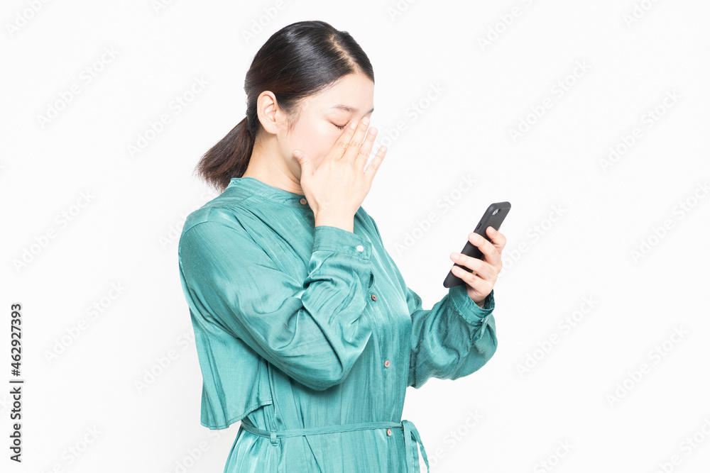 スマホを操作しながら泣いている主婦 スマホを操作しながら泣いている主婦
