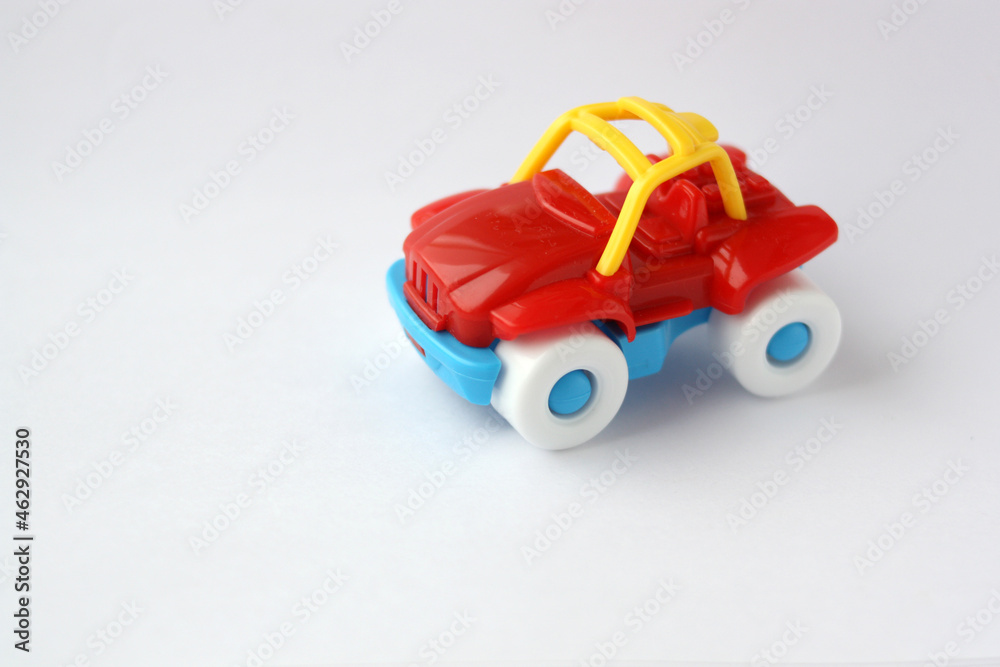 Children's toy plastic red car on a white background. There is free space for text. Close-up. Children's toy plastic red car on a white background. There is free space for text. Close-up.