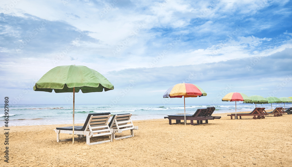 Sunbeds with sun umbrellas on an empty tropical beach, Sri Lanka.