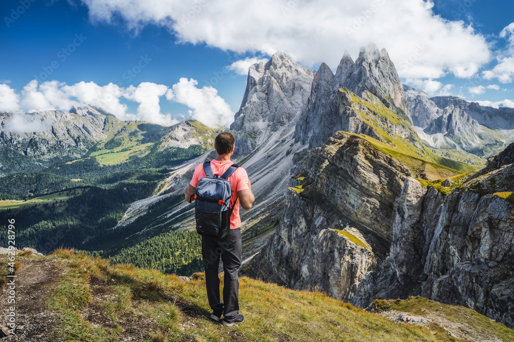 A man with backpack enjoy landscape of Seceda peak in Dolomites Alps, Odle mountain range, South Tyrol, Italy, Europe. Travel vacation concept