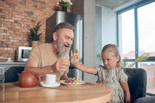 Family having breakfast together and dad trying to feed his daghter photo