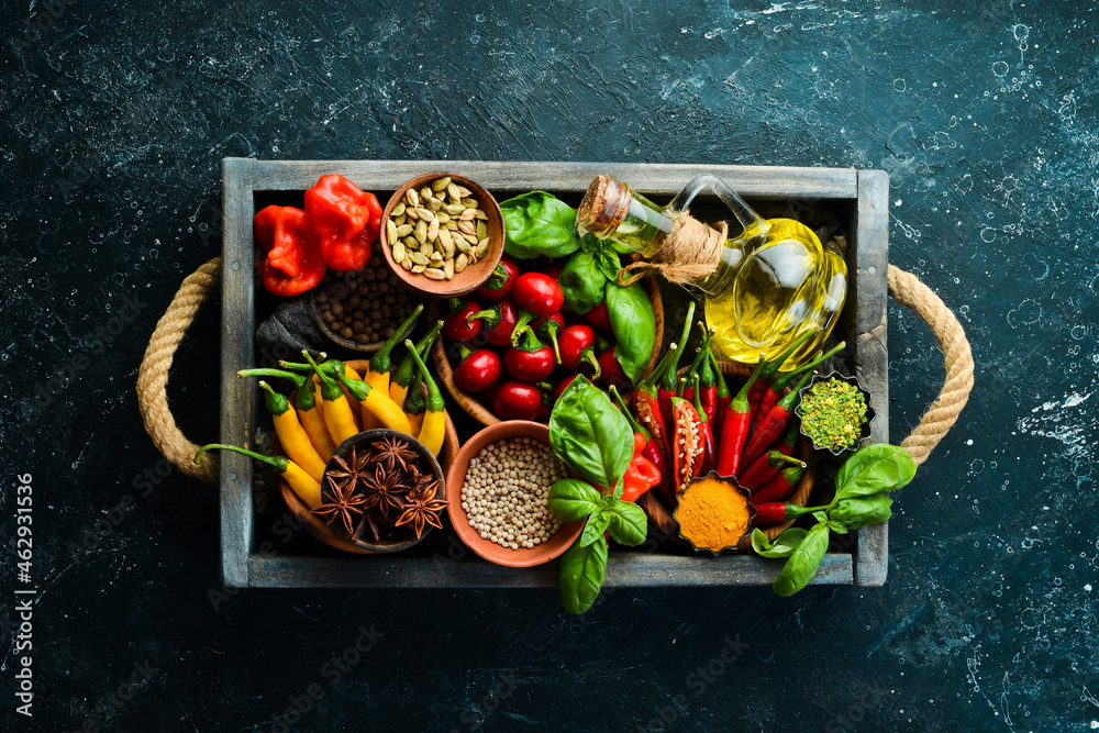 Spices in a wooden box: basil, pepper, oil, paprika, herbs. Food background. Top view.