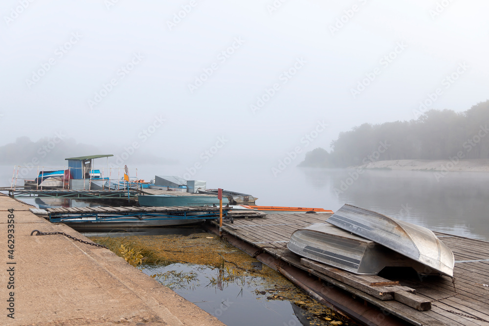 Fishing boats, small boats, moored to the pier in thick fog.