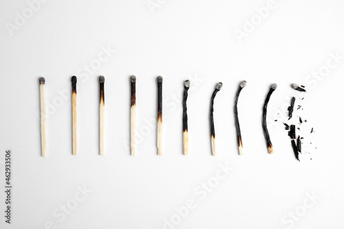 Different stages of burnt matches on white background, flat lay
