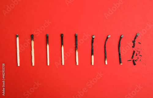 Fototapeta Naklejka Na Ścianę i Meble -  Different stages of burnt matches on red background, flat lay