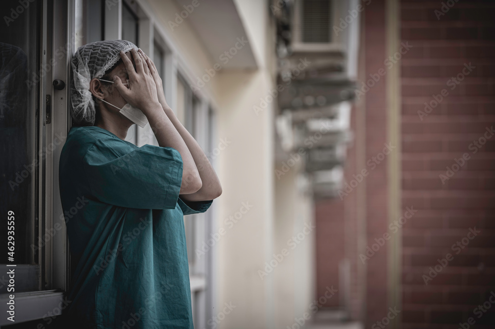Tired depressed female asian scrub nurse wears face mask blue uniform sits on hospital floor,Young woman doctor stressed from hard work Tired depressed female asian scrub nurse wears face mask blue uniform sits on hospital floor,Young woman doctor stressed from hard work