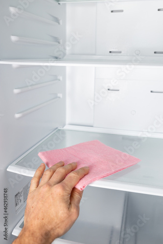 Man's hand cleaning fridge. Regular cleaning home refrigerator inside.