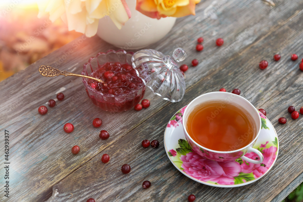 Tea in a beautiful cup and cranberry marmalade in the autumn garden. Tea in a beautiful cup and cranberry marmalade in the autumn garden.