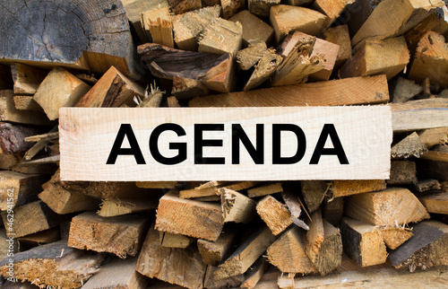 Wall firewood. Background of dry chopped firewood logs in a pile and plate with text Agenda