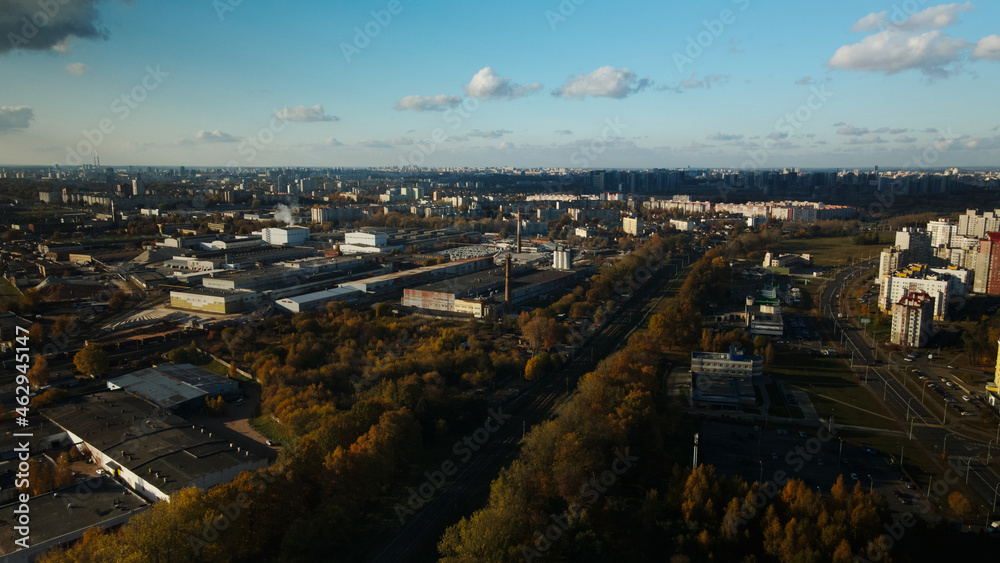 Flight over the autumn park. Trees with yellow autumn leaves are visible. On the horizon there is a blue sky and city houses. The park river is visible. Aerial photography.