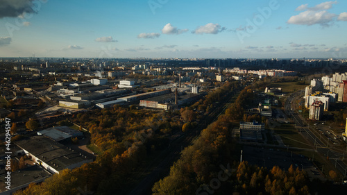 Fototapeta Naklejka Na Ścianę i Meble -  Flight over the autumn park. Trees with yellow autumn leaves are visible. On the horizon there is a blue sky and city houses. The park river is visible. Aerial photography.