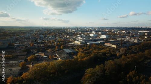 Fototapeta Naklejka Na Ścianę i Meble -  Flight over the autumn park. Trees with yellow autumn leaves are visible. On the horizon there is a blue sky and city houses. The park river is visible. Aerial photography.