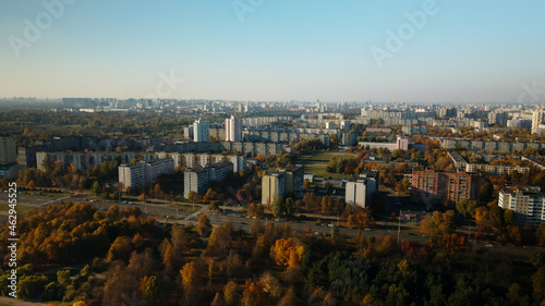 Flight over the autumn park. Trees with yellow autumn leaves are visible. On the horizon there is a blue sky and city houses. Aerial photography.