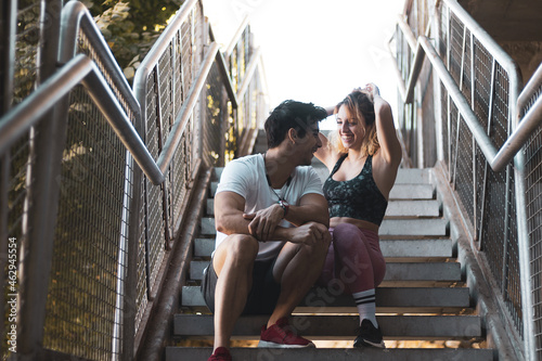 a couple talking on some stairs after doing sports.