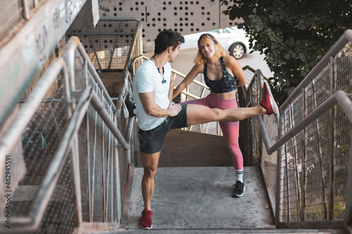 a young couple stretching in the middle of the street before exercising. 