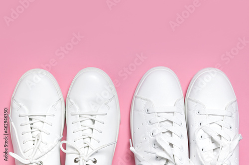 White women's leather sneakers on pink background top view flat lay. Stylish youth sneakers, sports shoes, genuine leather footwear. Minimalistic shoe store advertising fashion style Shoe background