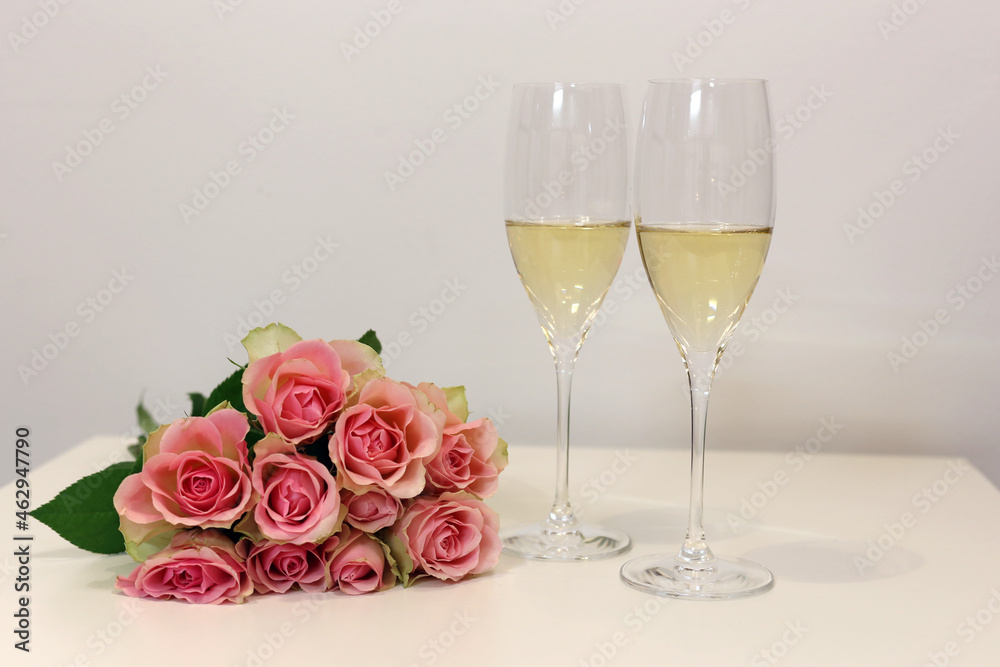 Two glasses of champagne and a bouquet of pink roses. Two glasses of champagne and a bouquet of pink roses.