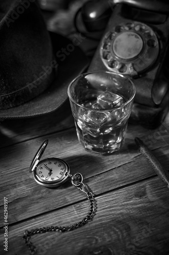 Old vintage cinematic noir scene, detective's desk with a hat, telephone, camera, portable cassette recorder, and whisky