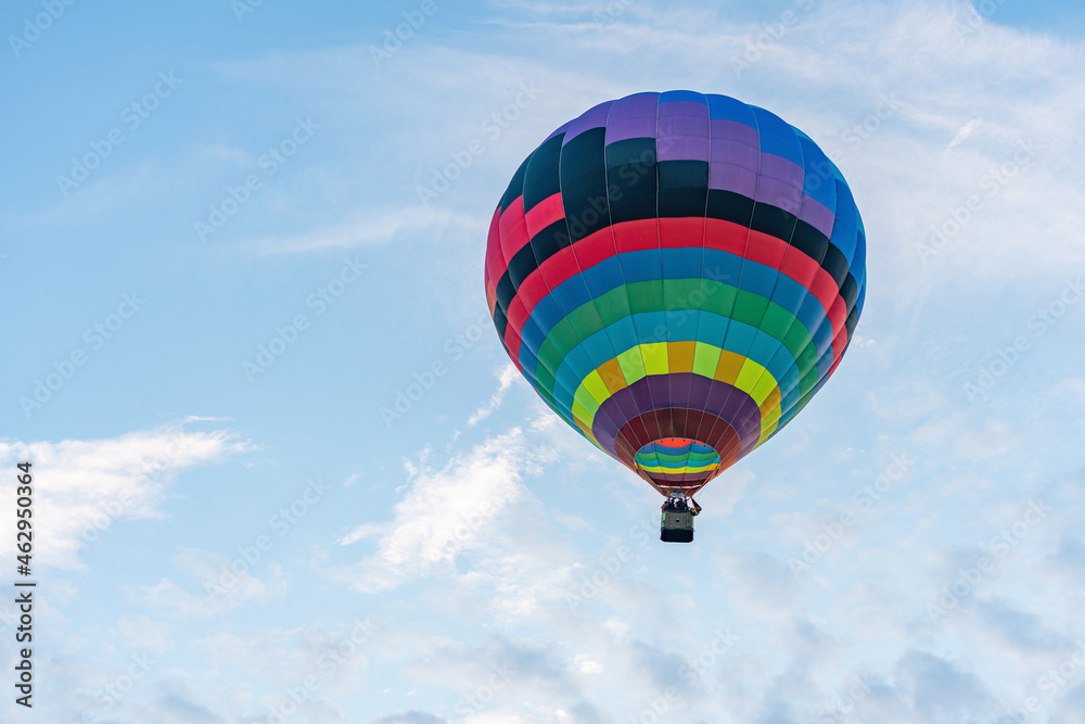 Obraz premium Multicolored hot air balloon on blue cloudy sky background