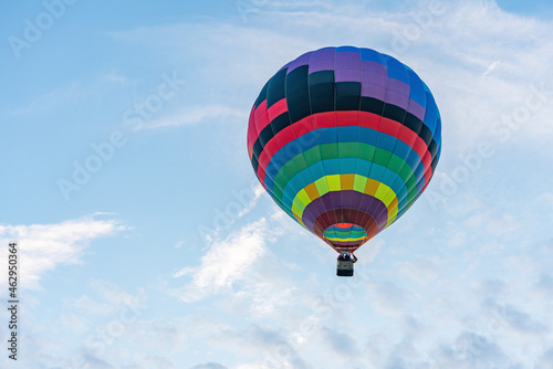 Multicolored hot air balloon on blue cloudy sky background