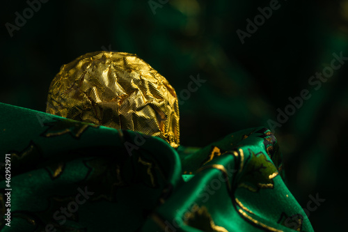 Tasty Chocolate Praline Wrapped with Golden Foil on Gorgeous Green Backdrop