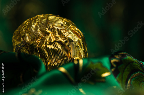 Tasty Chocolate Praline Wrapped with Golden Foil on Gorgeous Green Backdrop