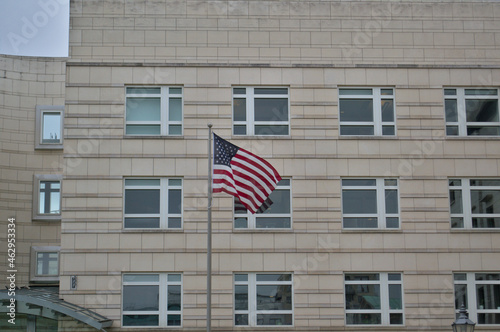 The American flag on the flagpole against the background of a multi-storey building.
