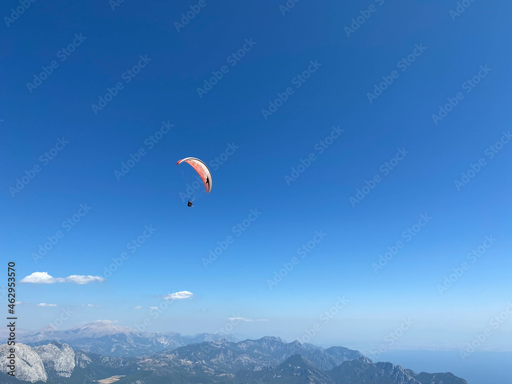 The parachutist flying high in the blue sky on a colorful parachute The parachutist flying high in the blue sky on a colorful parachute