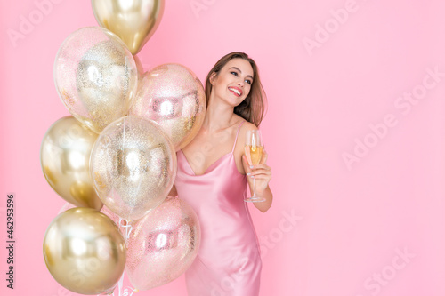 Smiling happy girl holds glass of champagne and many air balloons. came to party. Celebration 