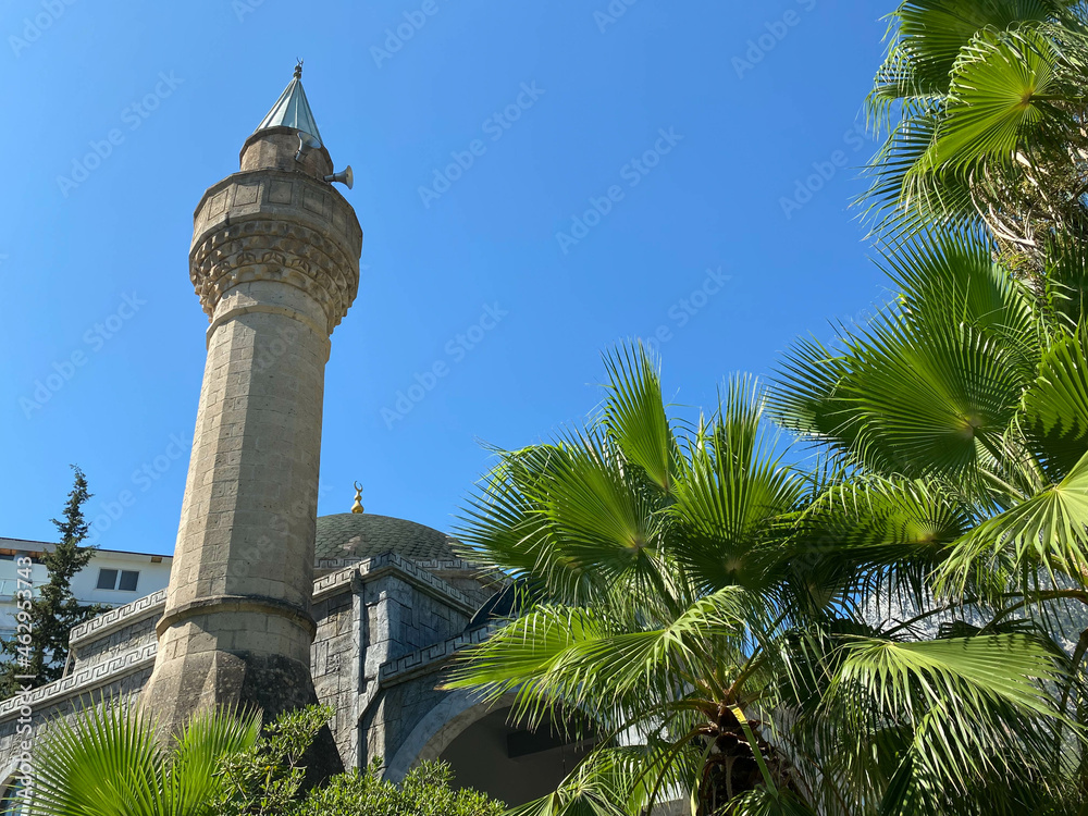 View of a beautiful ancient mosque in the Arabian style, a temple for prayers of Muslims in a tropical warm country with palm trees