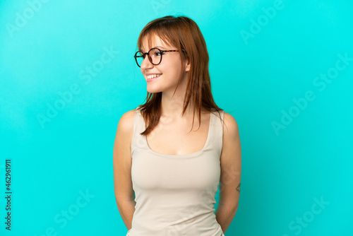 Redhead girl isolated on blue background looking side © luismolinero