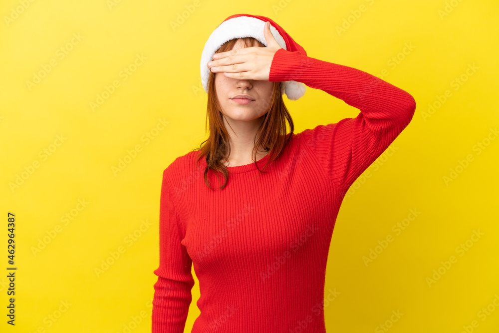 Redhead girl with christmas hat isolated on yellow background covering eyes by hands. Do not want to see something Redhead girl with christmas hat isolated on yellow background covering eyes by hands. Do not want to see something