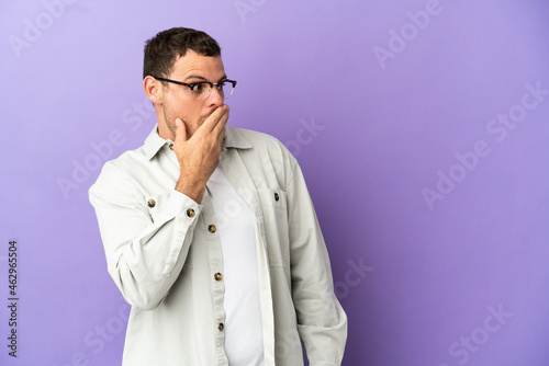 Brazilian man over isolated purple background doing surprise gesture while looking to the side