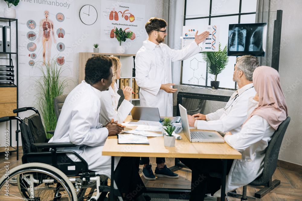 Group of multiracial medical workers discussing gene modification while sitting together at bright office. Qualified doctors researching dna peculiarities during international conference. Group of multiracial medical workers discussing gene modification while sitting together at bright office. Qualified doctors researching dna peculiarities during international conference.