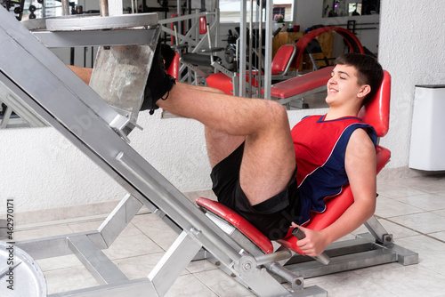 young muscular man doing physical activity in a gym, with machines and weights for a healthy life photo