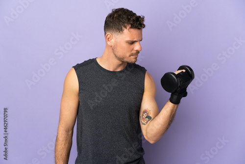 Young caucasian handsome man isolated on purple background making weightlifting