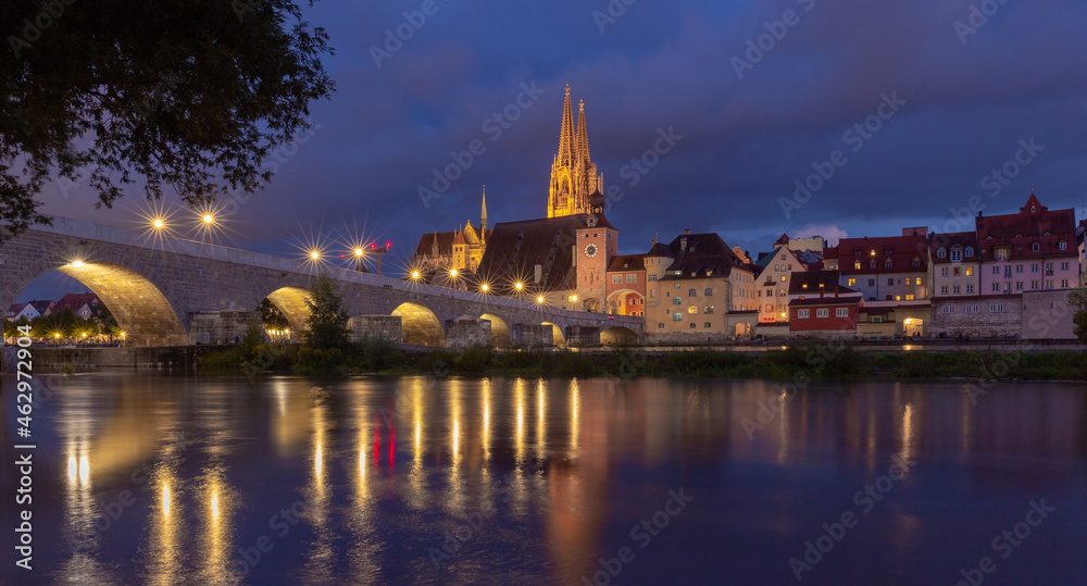 Regensburg. Old stone bridge over the Danube river in the night light.