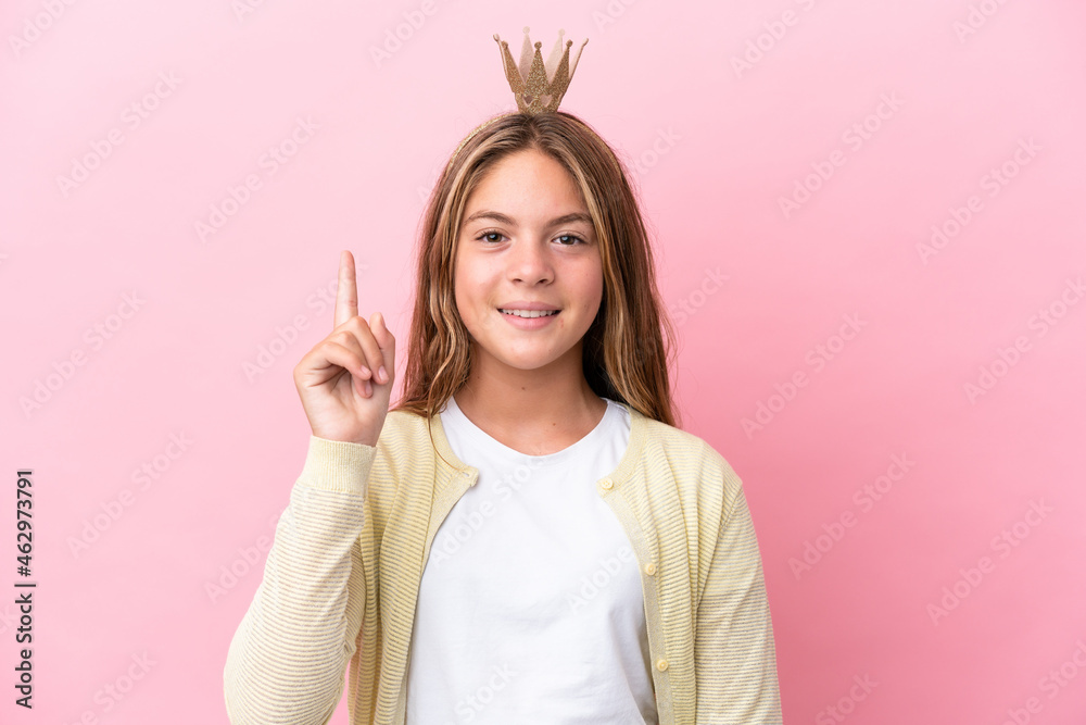 Little princess with crown isolated on pink background pointing up a great idea