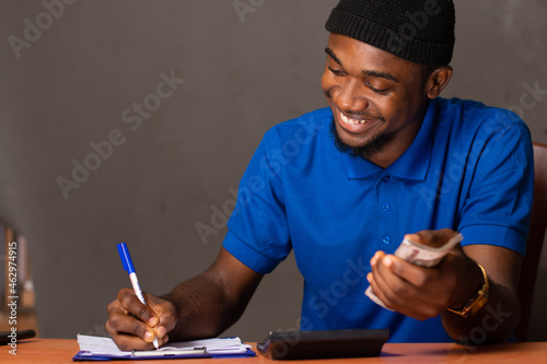 happy young black man doing some financial calculations