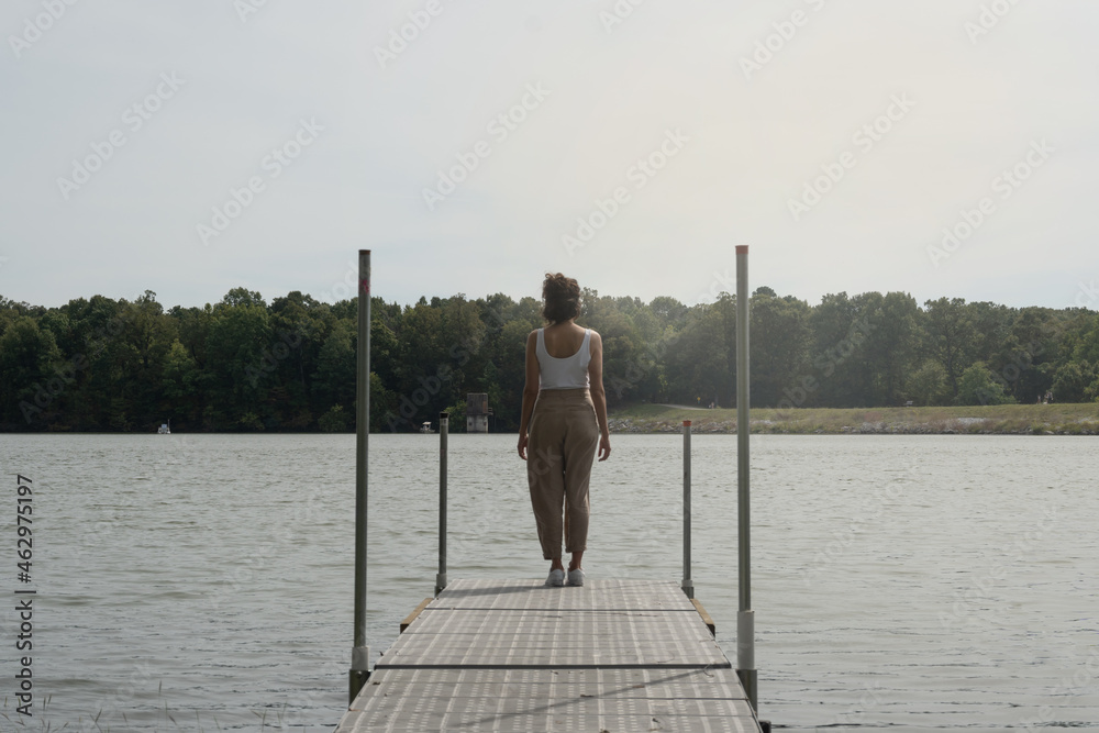 Unrecognizable woman on her back on a dock in front of a lake, concept freedom